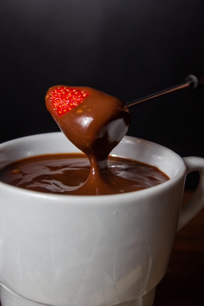 tasa con fondue de chocolate y una fresa cubierta en chocolate